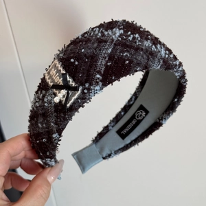 Detail of tweed headband with black bow, white pearls, and lace patch in hand