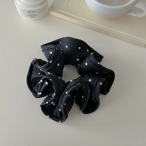 Detailed texture of a large black and white polka dot scrunchie on a cozy desk