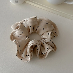 Detailed view of beige polka dot silk scrunchie on white background with elegant props