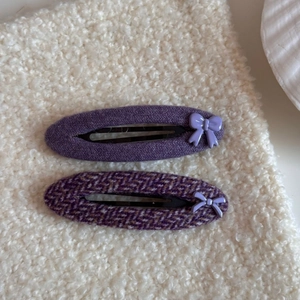 Primer plano de clips de pelo en tela de espiga púrpura con lazos 3D en color lavanda