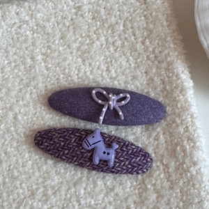 Detalle de horquillas moradas con lazo de lunares y textura de tela de tweed suave