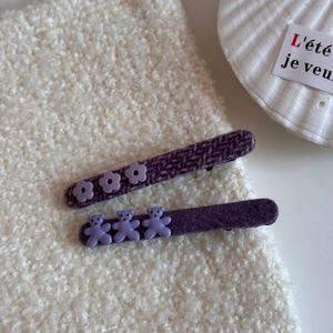 Detalle de horquillas de tela morada con flores y ositos de resina sobre felpa suave