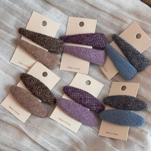 Dettaglio di tre paia di fermagli per capelli in tweed marrone, blu e viola su cartoncino