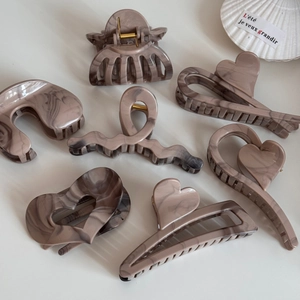 Detail of seven khaki marble pattern claw clips showing textures and varied geometric shapes