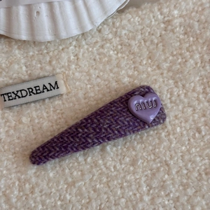 Detalle de pinza para el pelo en tweed morado con dije de corazón y diseño de pico