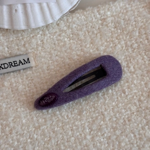 Primer plano de pasador de pelo violeta en tejido de espiga con grabado coreano