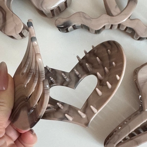 Detail of marble acetate hair claw clips with khaki ink patterns and non-slip teeth design