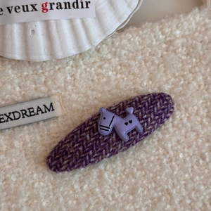 Detalle macro de una pinza de pelo de tweed violeta con un lindo adorno de perrito lavanda