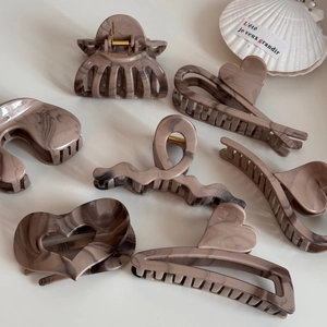 Macro detail of khaki marble acetate claw clips with elegant glossy finish and shell decor
