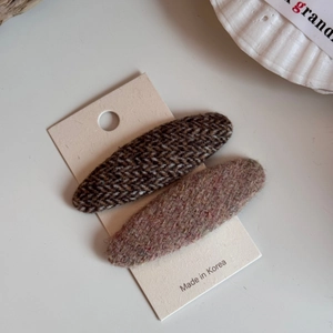 Dettaglio di fermagli per capelli in tessuto tweed e spina di pesce su carta