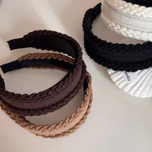 Detailed view of knitted cable twist headbands in brown, beige and black tones