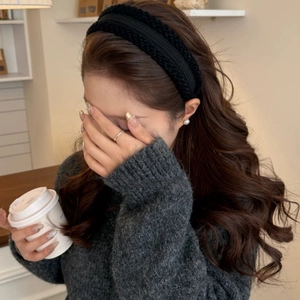 Close-up of black cable knit headband with soft texture on a female model in a cafe