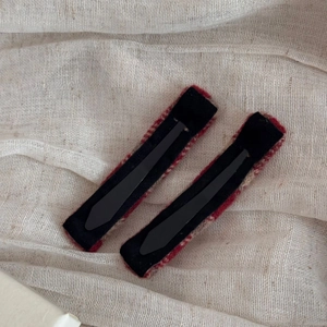 Detail showing two red plaid tweed hair clips with black velvet backing and metal duckbill