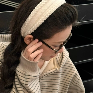 Detailed close-up of a chunky cable-knit cream headband showing its soft texture and weave