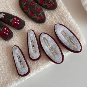 Detail view of vintage knitted strawberry embroidery on brown oval snap hair clips