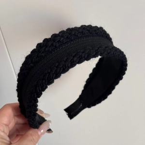 Close-up of thick black knitted headband with braided texture for winter warmth