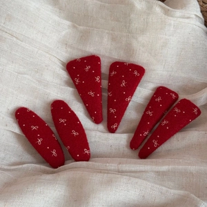 Dettaglio di 6 fermagli per capelli in feltro rosso con ricamo a fiocco bianco