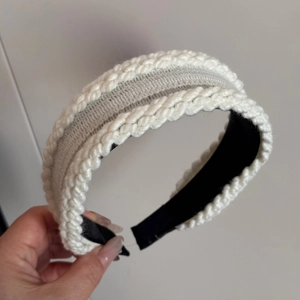 Close-up of white knitted twist headband featuring soft wool texture and black inner lining