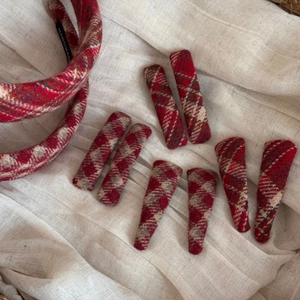 Detail of handmade red plaid wool hairband and matching clips on a soft beige background