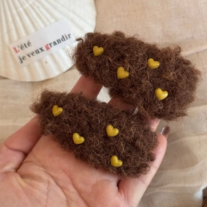 Nahaufnahme brauner Plüsch-Haarspangen mit Herzen auf weißem Tablett, Winter-Stil