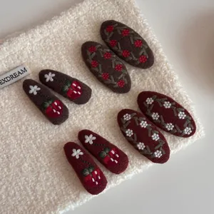 Detail of vintage embroidered floral snap hair clips with strawberry patterns on soft fabric