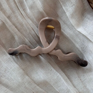 Detailed view of large marble texture khaki hair claw clip on neutral linen fabric