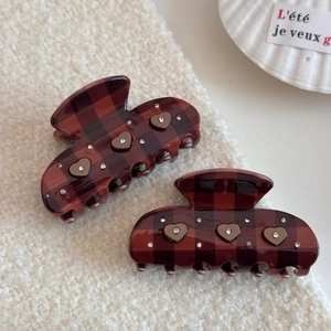 Detail of red-brown checkered claw clips with heart-shaped rhinestones and metallic trim