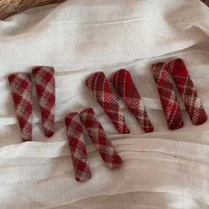 Detailed macro view of red plaid wool tweed hair clips on a soft beige fabric background