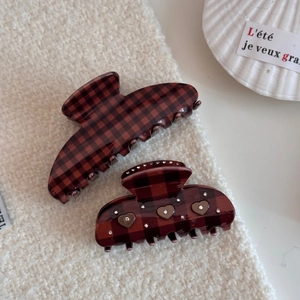 Detail of red and black checkered hair claws with sparkling heart-shaped rhinestone accents
