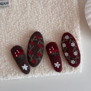 Detailed close-up of four vintage embroidered hair clips with floral and mushroom patterns
