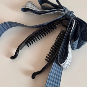 Détail d'une grande pince à cheveux banane avec ruban à carreaux bleu et dentelle