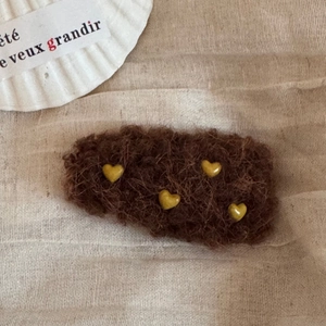 Detail der kaffeebraunen Plüsch-Herz-Haarklammer auf weichem Leinenhintergrund