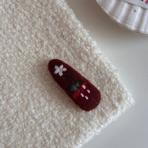 Detail of burgundy embroidered hair clip with strawberry and white flower patterns