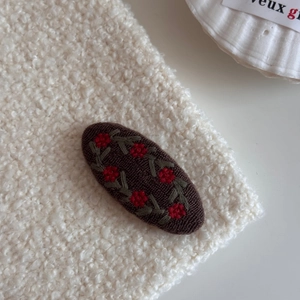 Macro shot of an oval vintage floral embroidery hair clip on a cozy cream background