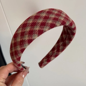 Close-up of a wide padded red and white plaid wool headband with a thick textured fabric