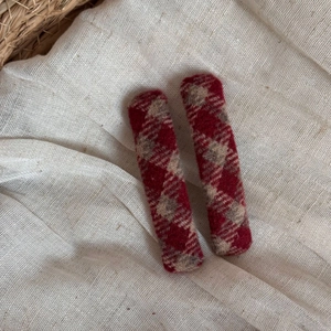 Detail of red and white plaid tweed hair clips on a soft beige natural linen background
