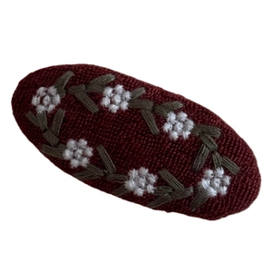 Vintage burgundy knit hair clip with floral embroidery on white background