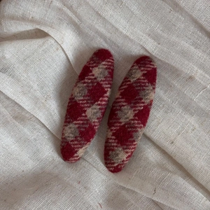 Detail of red and white plaid wool tweed hair clips with elegant textured fabric on linen background