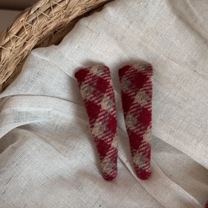 Close-up of red plaid wool hair clips with detailed vintage texture and soft fabric