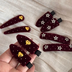 Detail of burgundy velvet hair clips with gold heart, star, and white polka dot patterns