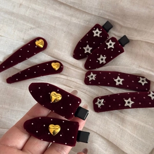 Detail of burgundy velvet hair clips with white dots, gold hearts and crystal stars