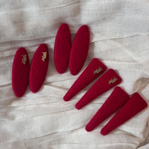 Red wool felt hair clips set with handmade gold metallic details on linen background