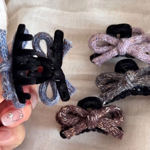Detail of four handmade knitted tweed bow hair claws in various autumn colors
