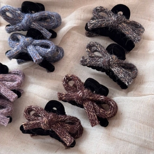 Detailed view of assorted wool yarn knitted bow hair clips in multiple vintage colors