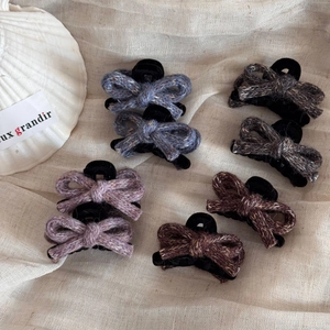 Set of 7 elegant knitted bow hair clips in autumn winter colors on linen background