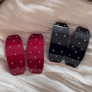 Détail de barrettes à cheveux avec strass brillants en rouge foncé et noir sur lin doux