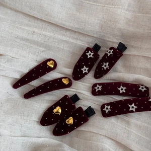 Close-up of burgundy velvet hair clips with white polka dots, stars, and heart charms