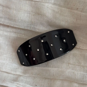 Détail d'une barrette élégante en résine noire ornée de strass brillants sur tissu texturé