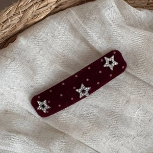 Close-up of burgundy velvet hair clip with pink polka dots and sparkling silver stars