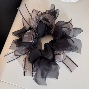 Detailed texture of black chiffon and silver satin bow scrunchie with wavy edges